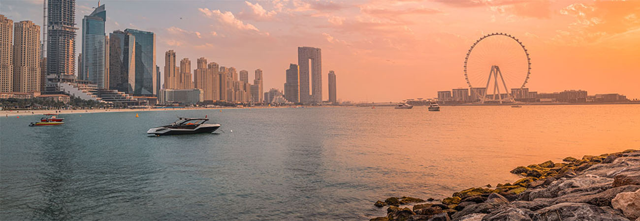 A delightful and colorful sunset over Blue waters Island with the famous Dubai Eye Ferris wheel. Panoramic view of the city in UAE